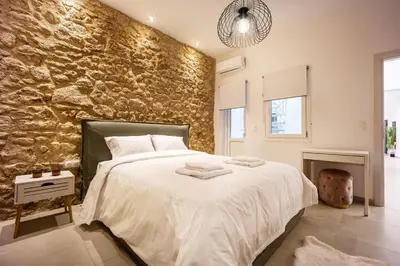 a bedroom with a large bed with a stone wall at Kastella Luxe Stone in Piraeus