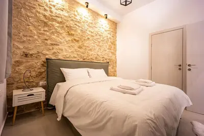 a bedroom with a white bed and a stone wall at Kastella Luxe Stone in Piraeus