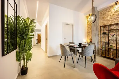 a dining room with a table and chairs and a plant at Kastella Luxe Stone in Piraeus