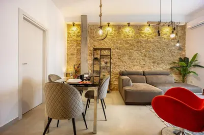 a living room with a couch and a table and chairs at Kastella Luxe Stone in Piraeus