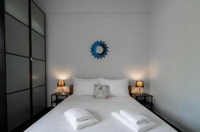 a white bed with two pillows and a clock on the wall at Villa PAPADATES NEFELI in Barbaliáki