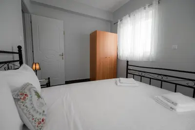a bedroom with a bed with white sheets and a window at Villa PAPADATES NEFELI in Barbaliáki