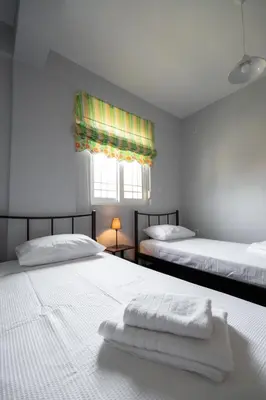 a bedroom with two beds with white sheets and a window at Villa PAPADATES NEFELI in Barbaliáki