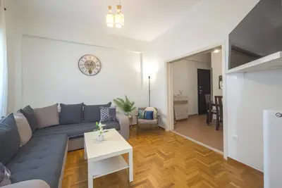 a living room with a blue couch and a table at Spacious Sunny Apartment in Athens