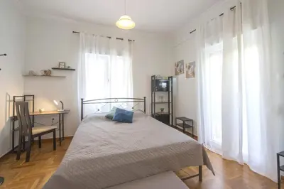a bedroom with a bed and a desk and windows at Spacious Sunny Apartment in Athens