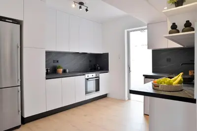 a kitchen with white cabinets and a black counter top at Athinais Park Acropolis View in Athens