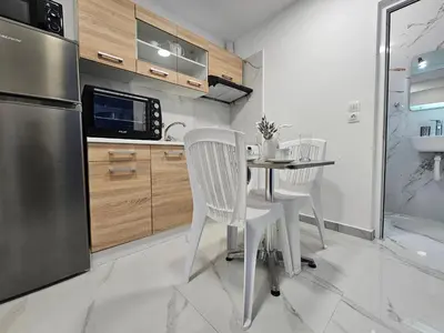 a kitchen with a table and chairs and a refrigerator at Agia Sofia Cycladic Suites in Piraeus