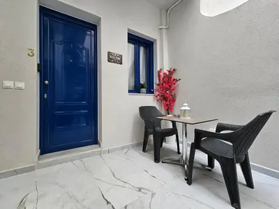 a blue door with chairs and a table with a vase of flowers at Agia Sofia Cycladic Suites in Piraeus
