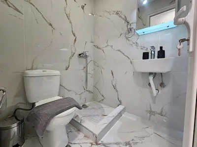a white bathroom with a toilet and a sink at Agia Sofia Cycladic Suites in Piraeus