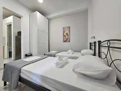 two beds in a bedroom with white walls at Agia Sofia Cycladic Suites in Piraeus