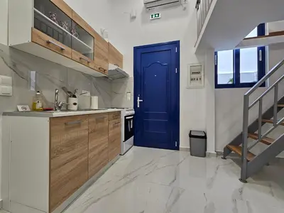 a kitchen with a blue door and a staircase at Agia Sofia Cycladic Suites in Piraeus