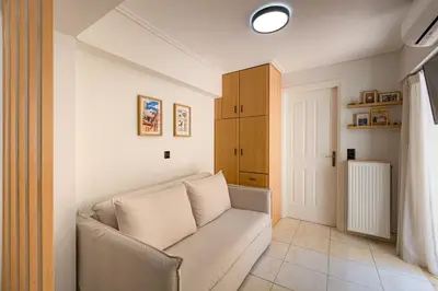a living room with a white couch and a door at Atherial Studio in Athens