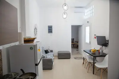 a kitchen and living room with a refrigerator and a table at Aimou Suites in Piraeus