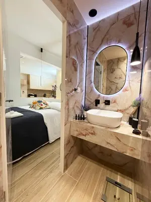 a bathroom with a sink and a bed and a mirror at Petit and Peaceful Retreat in Athens