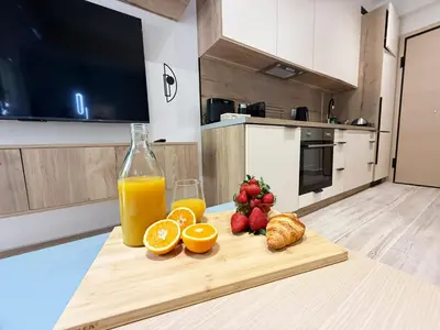 a cutting board with fruit and a bottle of orange juice at Petit and Peaceful Retreat in Athens