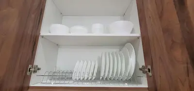 a cupboard with white plates and bowls on it at A few minutes from Siggrou Street in Athens