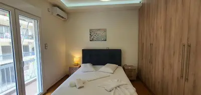 a bedroom with a bed with white sheets and a window at A few minutes from Siggrou Street in Athens