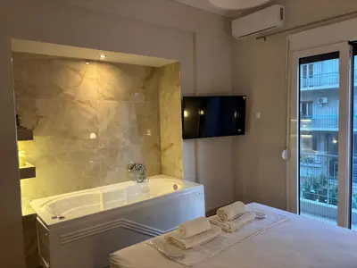 a bathroom with a tub and a bed with towels at Elysian Αpartment II in Athens