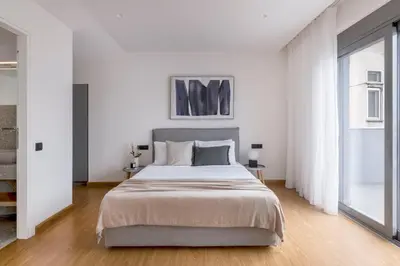 a white bedroom with a large bed and a window at The Exarchia Hideout by UPSTREET in Athens