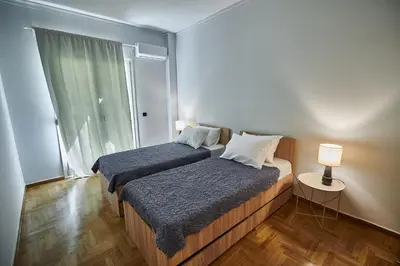 two beds in a small room with a window at Brand new Athens Museum Apt in Athens