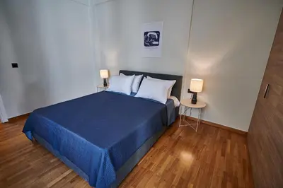 a bedroom with a blue bed with two white pillows at Brand new Athens Museum Apt in Athens