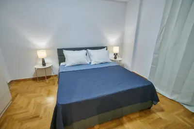 a bedroom with a blue bed with two lamps at Brand new Athens Museum Apt in Athens
