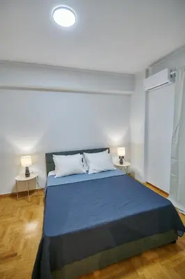 a bedroom with a blue bed with two lamps at Brand new Athens Museum Apt in Athens