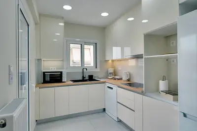 a white kitchen with white cabinets and a window at Seaside bliss in Alimos ideal for families ! in Athens