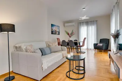 a living room with a white couch and a table at Seaside bliss in Alimos ideal for families ! in Athens