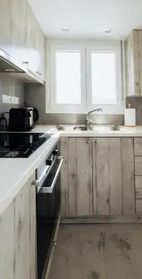 a kitchen with wooden cabinets and a sink and two windows at Villa PAPADATES ARTEMIS in Barbaliáki