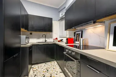 a kitchen with black cabinets and white counter tops at Contempo Athens in Athens