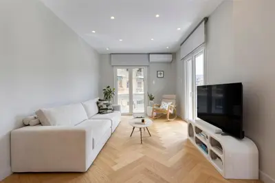 a living room with a white couch and a flat screen tv at Spacious Athenian escape, Koukaki in Athens