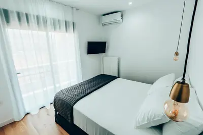 a white bedroom with a bed and a window at Dreamy Glyfada Apartment in Athens