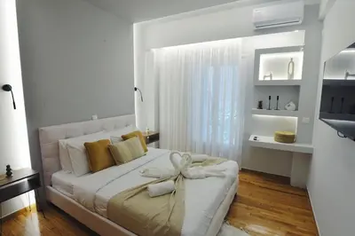 a white bedroom with a bed with a bow on it at Seren Studio near Victoria Metro-Earthy Tones & Comfort in Mesochórion