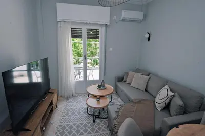 a living room with a couch and a television at Seren Studio near Victoria Metro-Earthy Tones & Comfort in Mesochórion