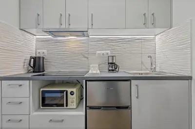 a white kitchen with a microwave and a sink at Kallari Serenity Apartment in Athens
