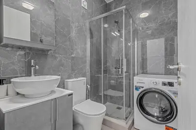 a bathroom with a toilet sink and a washing machine at Kallari Serenity Apartment in Athens