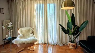 a living room with a chair in front of a window at Avenue of Gods - Irakli's Retreat in Athens