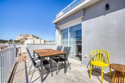 a patio with a wooden table and chairs on a balcony at Avra - Topfloor apartment in historical Athens in Athens