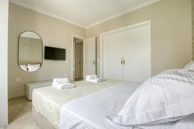 a white bedroom with two beds and a mirror at Avra - Topfloor apartment in historical Athens in Athens