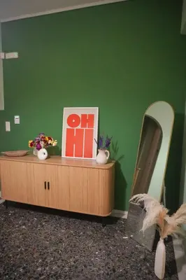 a room with a green wall and a table with a mirror at The Green Apartment Athens in Athens