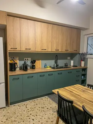 a kitchen with green cabinets and a wooden table at The Green Apartment Athens in Athens