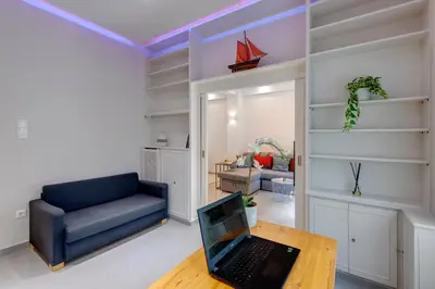a living room with a blue couch and a laptop on a table at Rafael Apartment Ampelokipoi in Athens