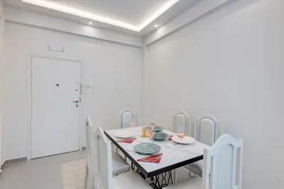 a white dining room with a table and chairs at Rafael Apartment Ampelokipoi in Athens