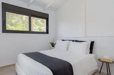 a white bed in a white room with a window at Athenian Black Villa in Saronida