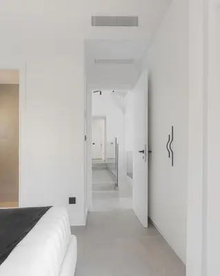 a white room with a bed and a hallway at Athenian Black Villa in Saronida