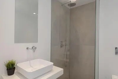 a white bathroom with a sink and a shower at Athenian Black Villa in Saronida