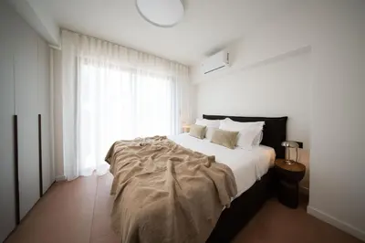 a white bedroom with a large bed and a window at Ikima Living in Piraeus
