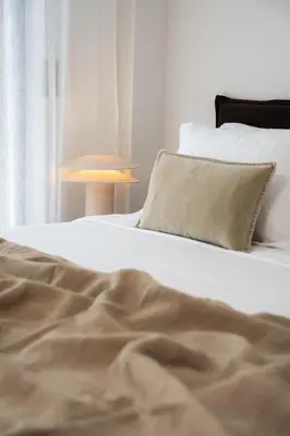 a white bed with a pillow and a lamp at Ikima Living in Piraeus