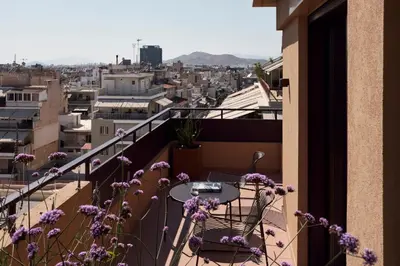 a balcony with a table and chairs and purple flowers at Ikima Living in Piraeus